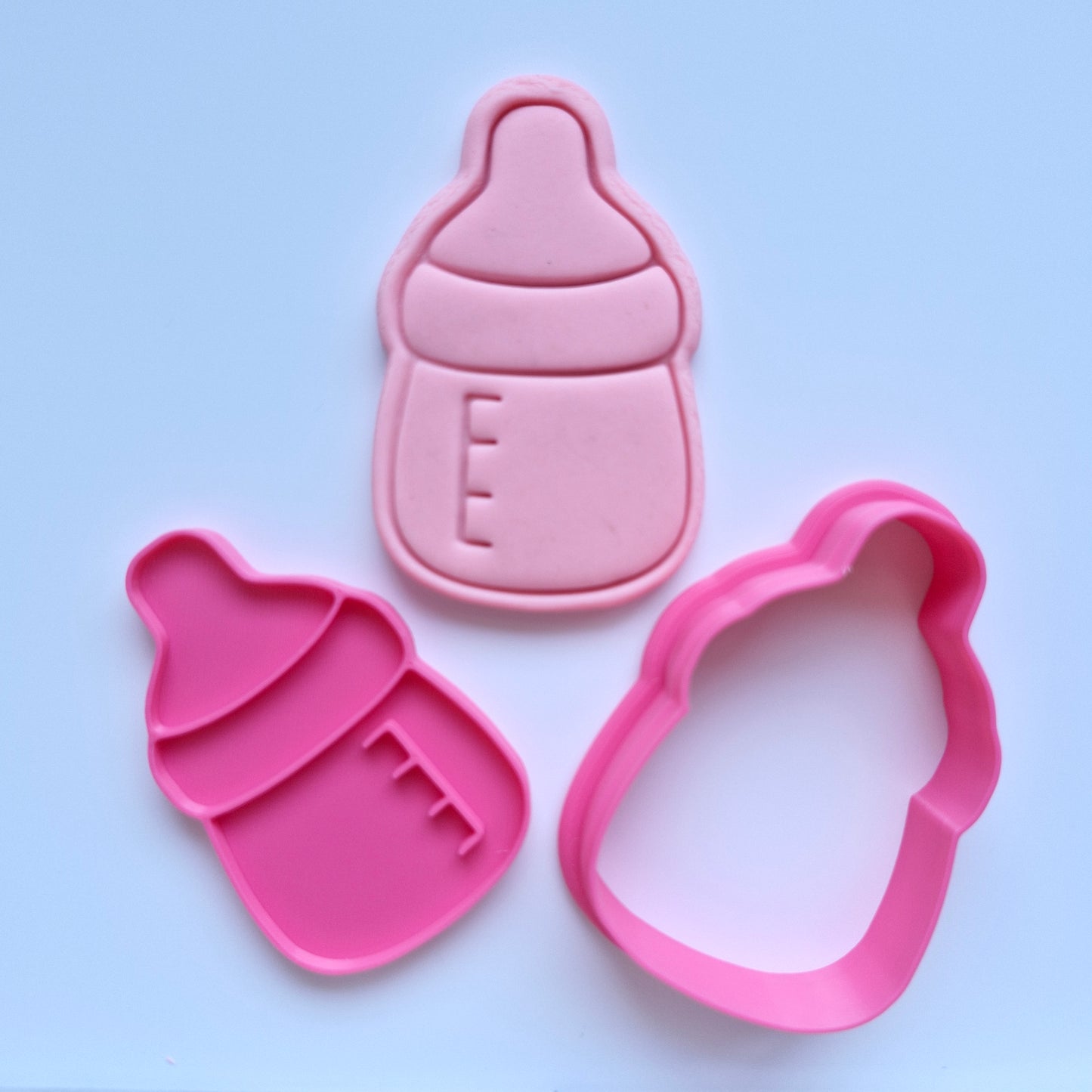 pink fondant, in the shape of baby bottle and stamped with the design on plain baby bottle, pink cookie cutter and stamp in the shape of baby bottle Simple Baby Bottle Cookie Cutter and Stamp