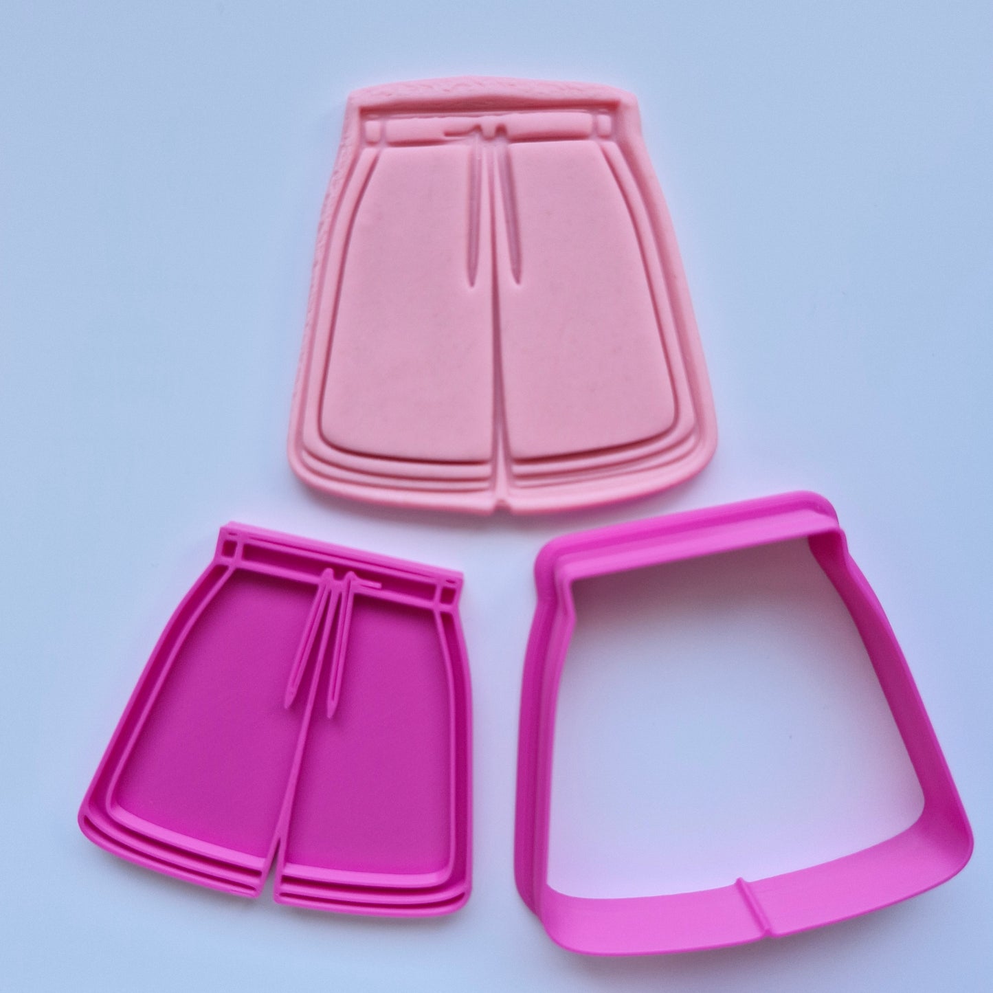 pink cookie cutter and stamp, with pink fondant of jersey sports shorts on white background. Activewear Outfit Set Cookie Cutter and Stamp Athletic Shorts Cookie Cutter and Stamp