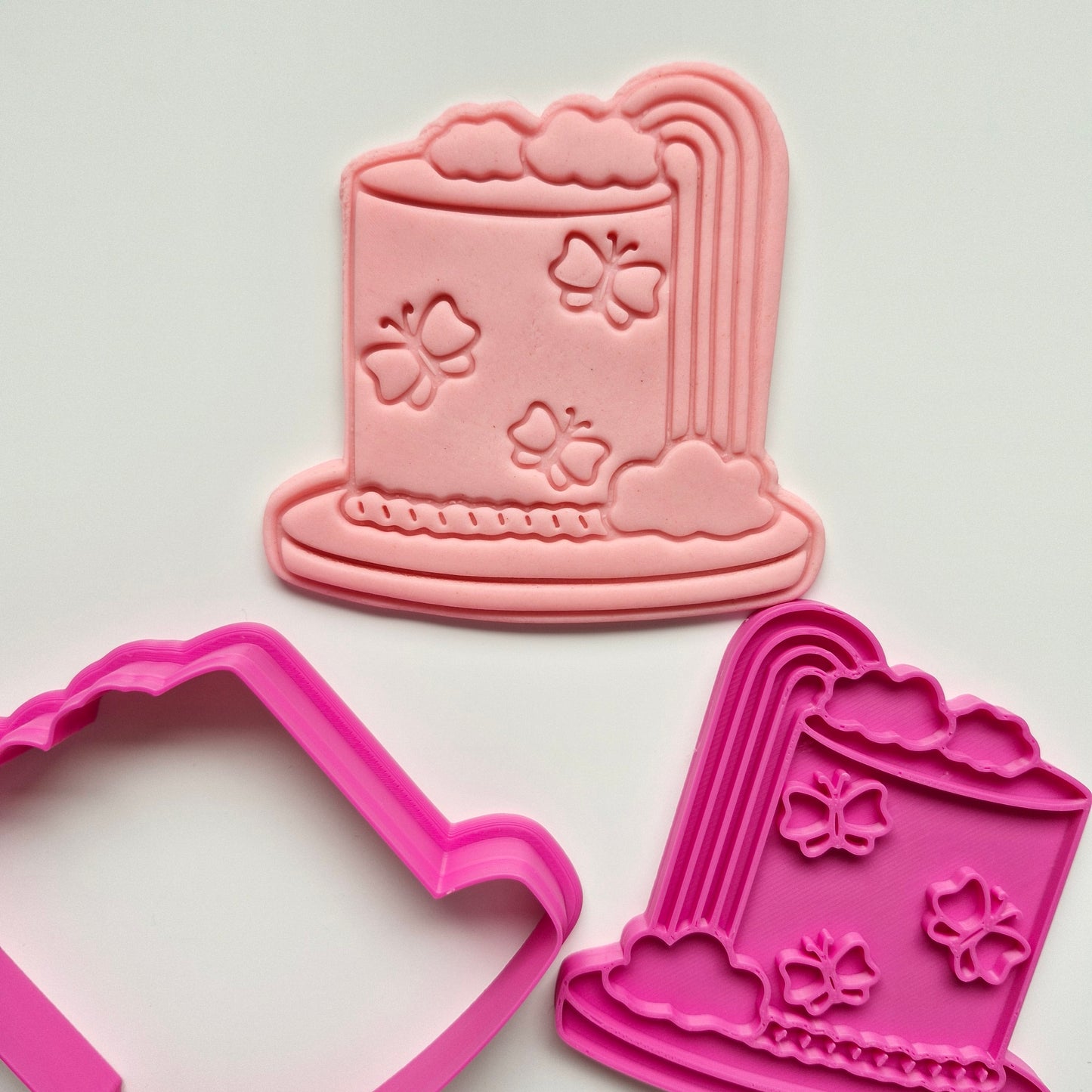 cookie cutter and stamp in the shape of rainbow cake with butterflies on it, stamped onto peach fondant, with white background. Rainbow, Butterfly Cake, Cookie Cutter and Stamp