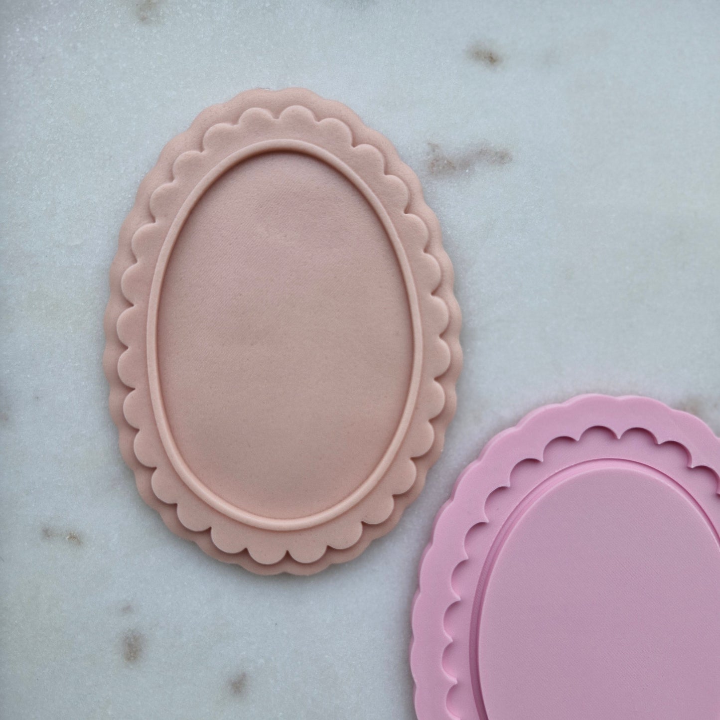 Two pink scalloped-edge silicone mats on a light gray surface Oval Plaque Frame, Cookie Cutter and Stamp