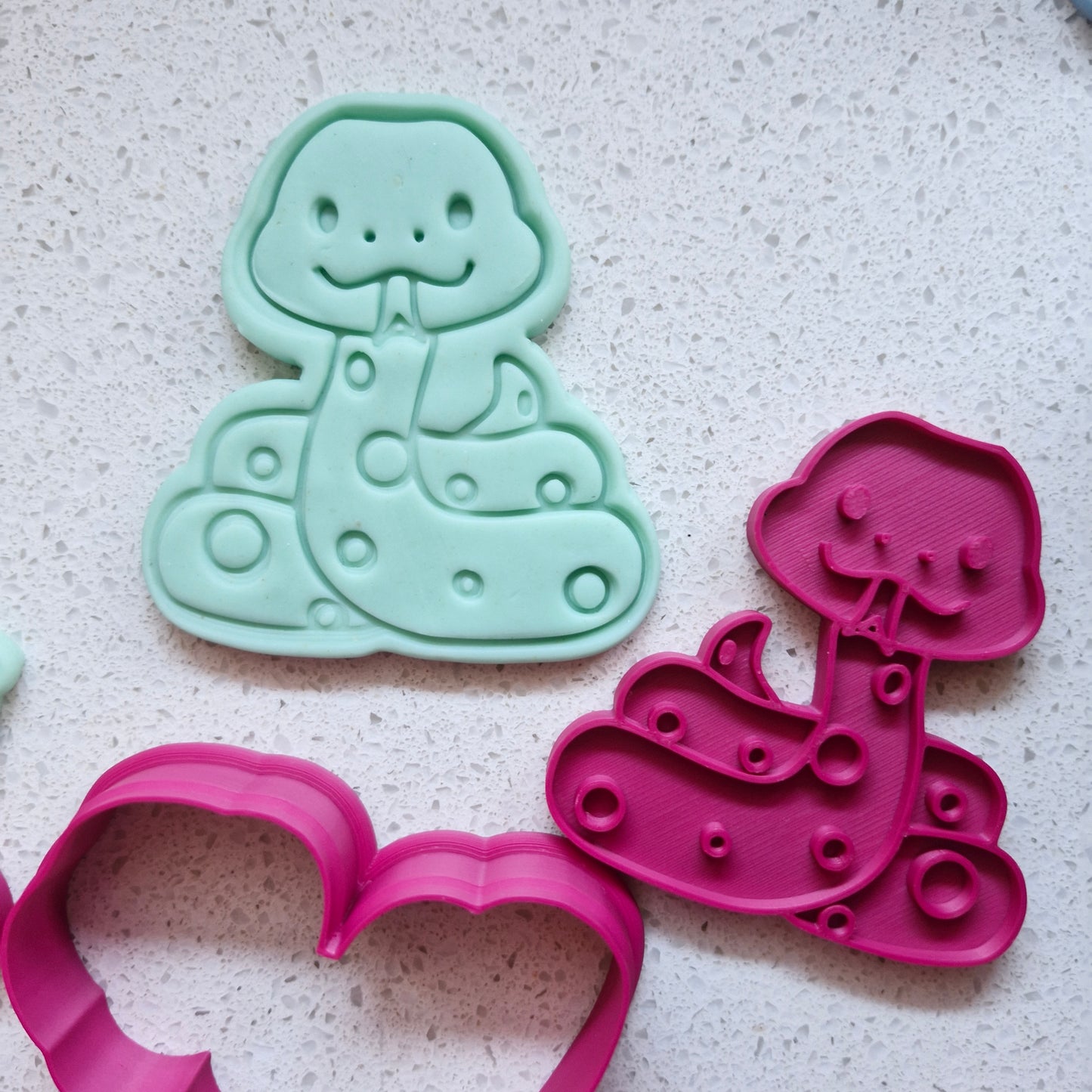 cookie cutter and stamp on green fondant making the shape of a cobra looking snake, on white speckled stone