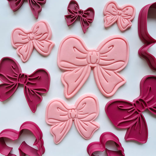 Pink and red bow-shaped cookie cutters on a white background of Cassey Bow, Cookie Cutter and Stamp