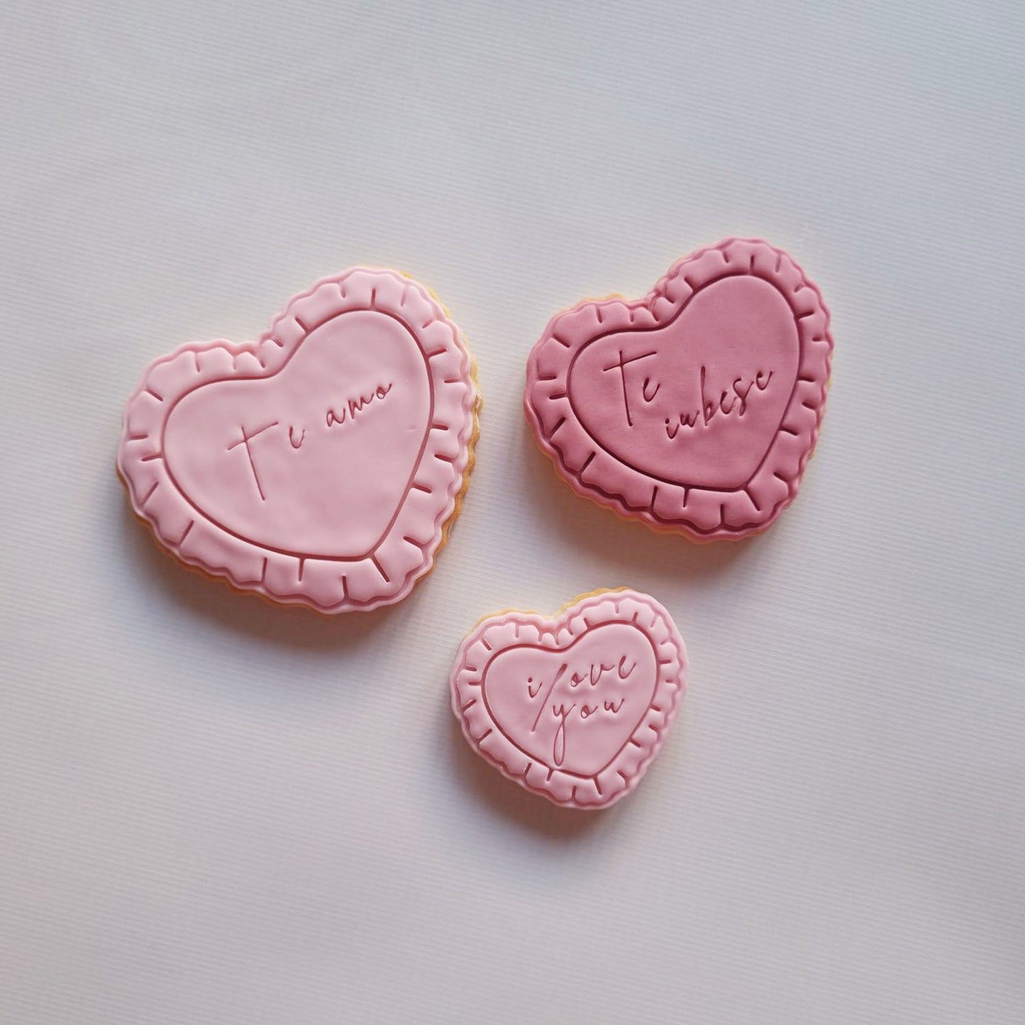 3 sugar cookies on a white background, they 3 love hearts with frills and writing I love you in 3 different languages Heart Frame with Frills Cookie Cutter and Stamp