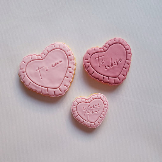 3 sugar cookies on a white background, they 3 love hearts with frills and writing I love you in 3 different languages Heart Frame with Frills Cookie Cutter and Stamp