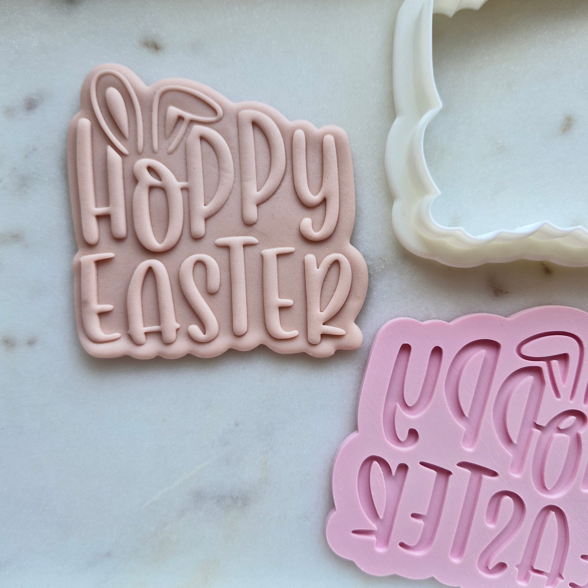 Pink 'Happy Easter' cookie cutter on a marble surface