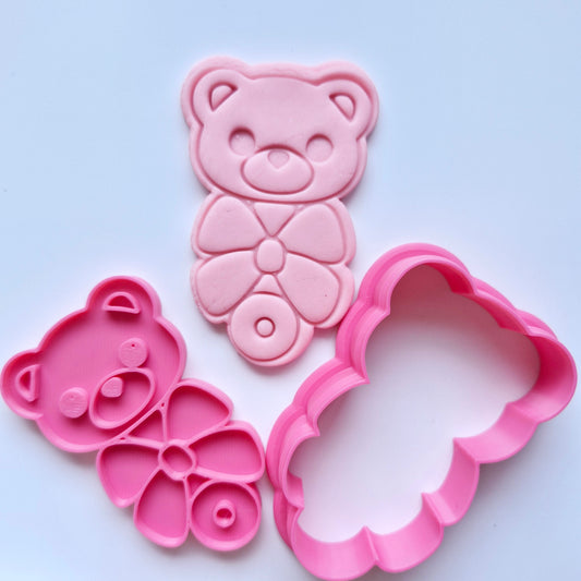 Bear Rattle With Bow Cookie Cutter and Stamp, pink cookie cutter and stamp, stamped on pink fondant with the design of a baby rattle with bear head and bow
