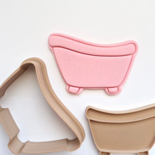 pink fondant, and brown cookie cutter and stamp in the shape and imprint of a bathtub, all on white background, zoomed in