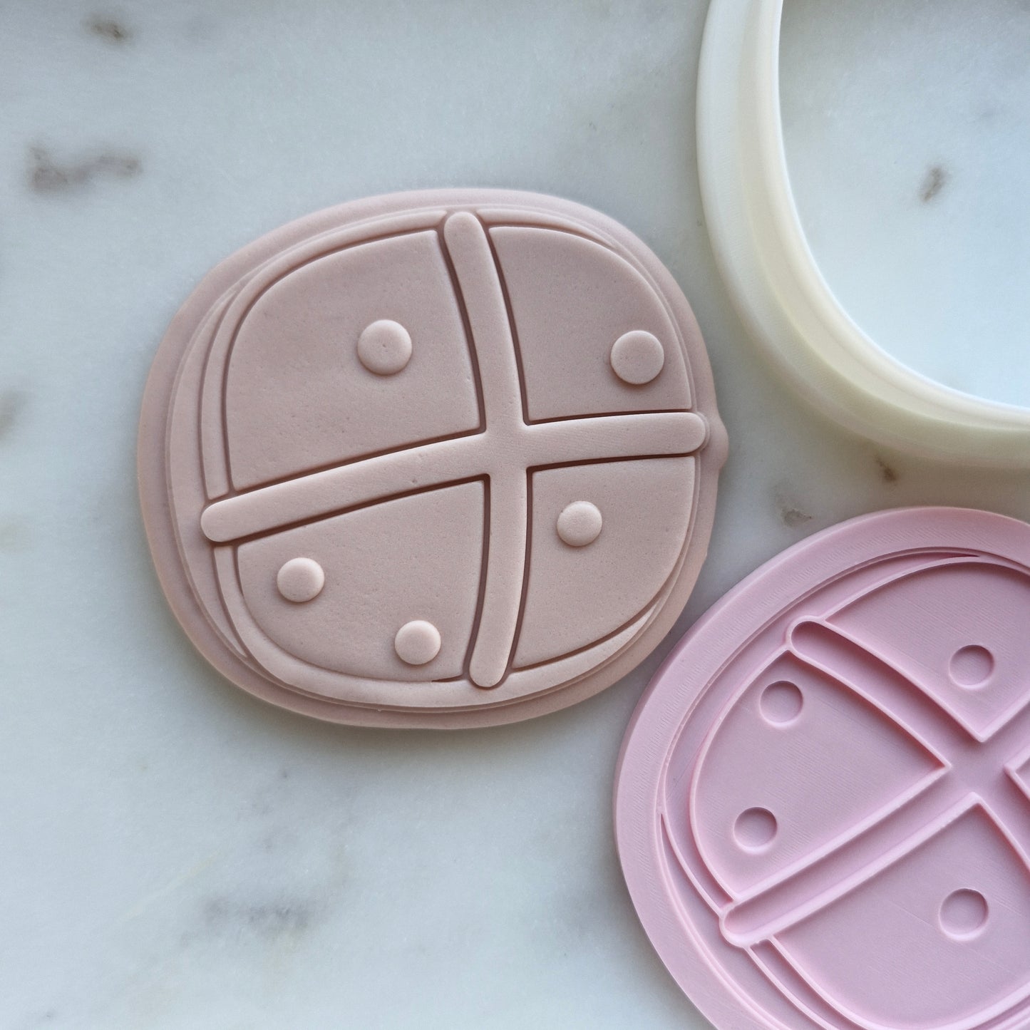 hot cross bun stamped on beige fondant by cookie cutter and stamp flat on white marble ston
