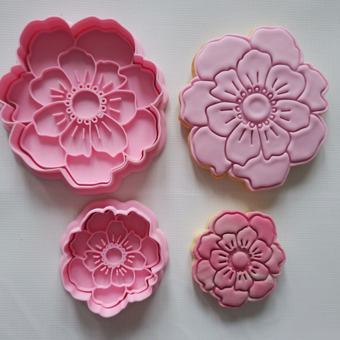 2 sugar cookies one large one small and 2 cookie cutters one large one small in the shape of peony flower and they are in shades of pink laying flat on white background Open Peony Flower Cookie Cutter and Stamp