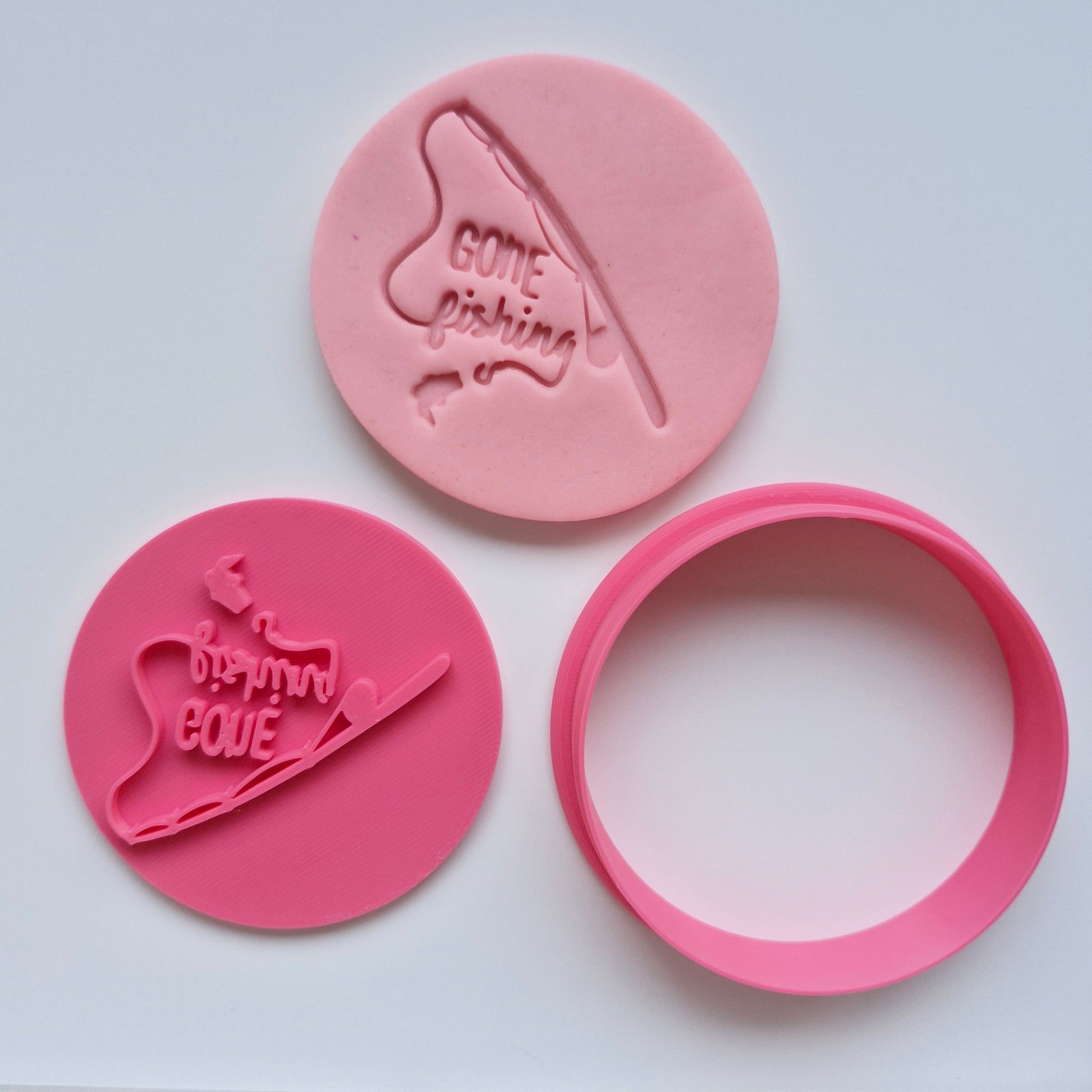 pink fondant and pink cookie cutter and stamp gone fishing, on white background