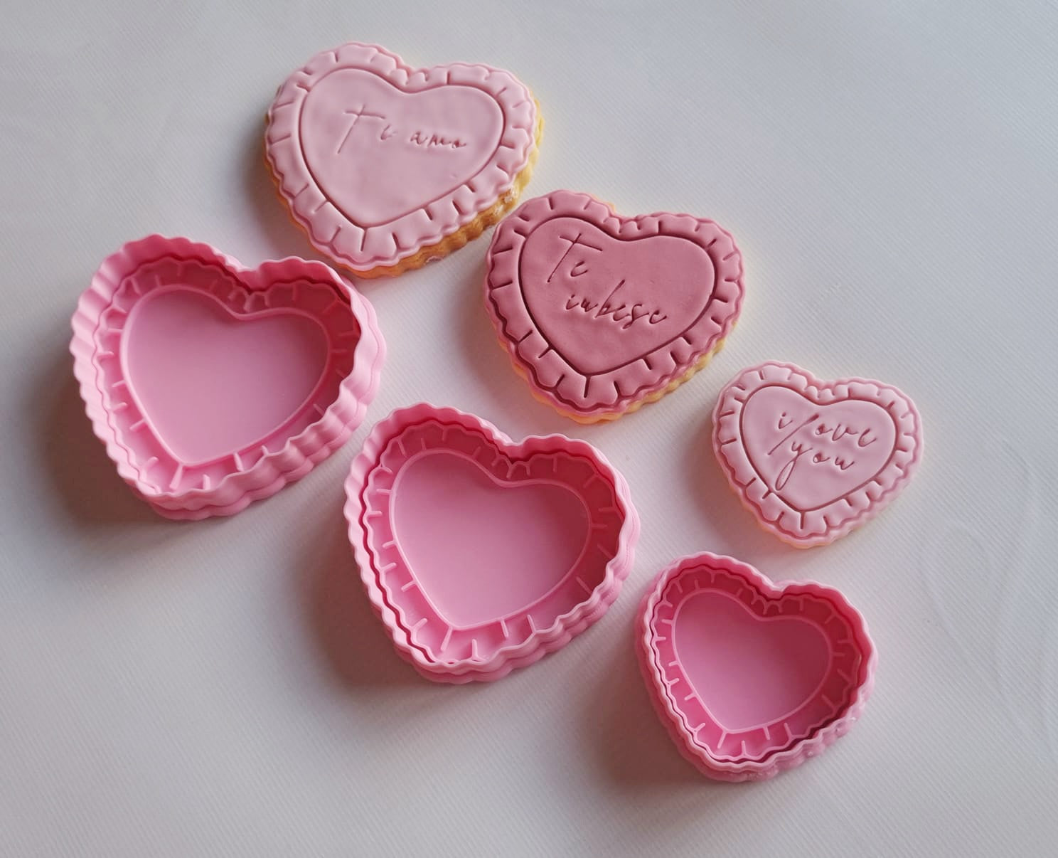 3 cookie cutters and stamps, 3 sugar cookies, in 3 different sizes, in the shape of heart with frills and I love you writing on them in different languages Heart Frame with Frills Cookie Cutter and Stamp
