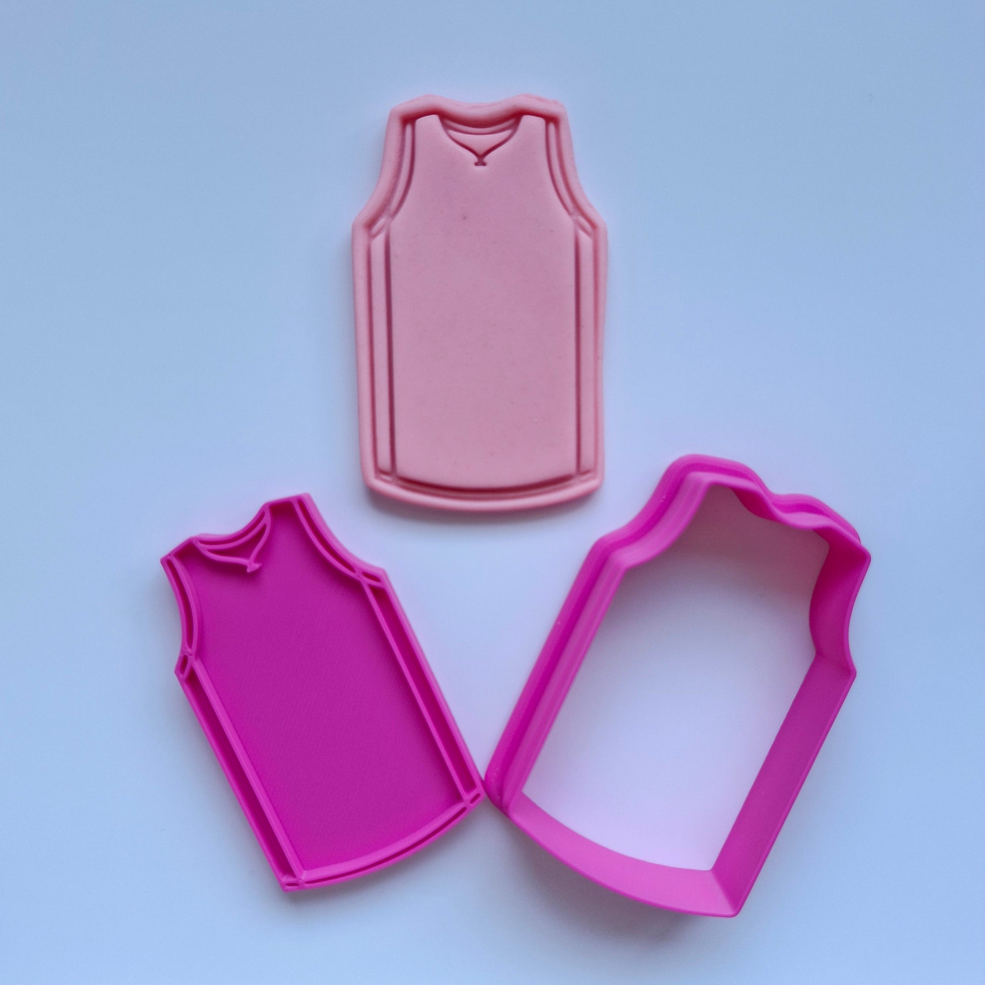 pink cookie cutter and stamp, with pink fondant in the shape of a sports jersey singlet. Jersey Singlet Cookie Cutter and Stamp. Activewear Outfit Set Cookie Cutter and Stamp