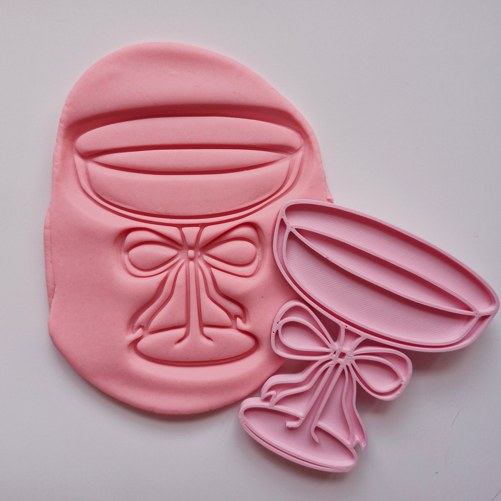 cookie stamp in the shape of martini glass with a bow, stamped on coral pink fondant on white background Martini Glass with Bow Cookie Cutter and Stamp