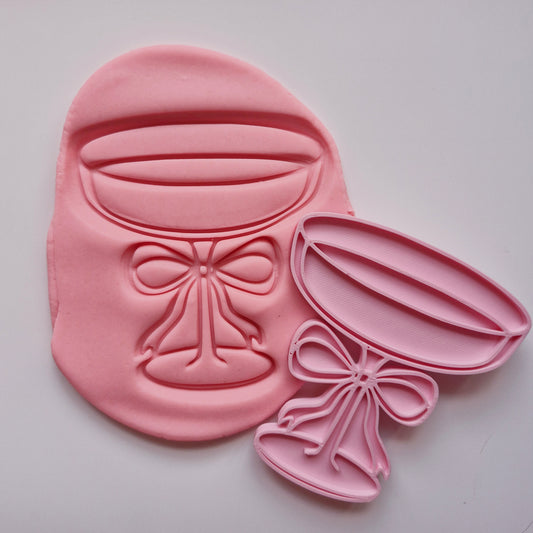 cookie stamp in the shape of martini glass with a bow, stamped on coral pink fondant on white background Martini Glass with Bow Cookie Cutter and Stamp