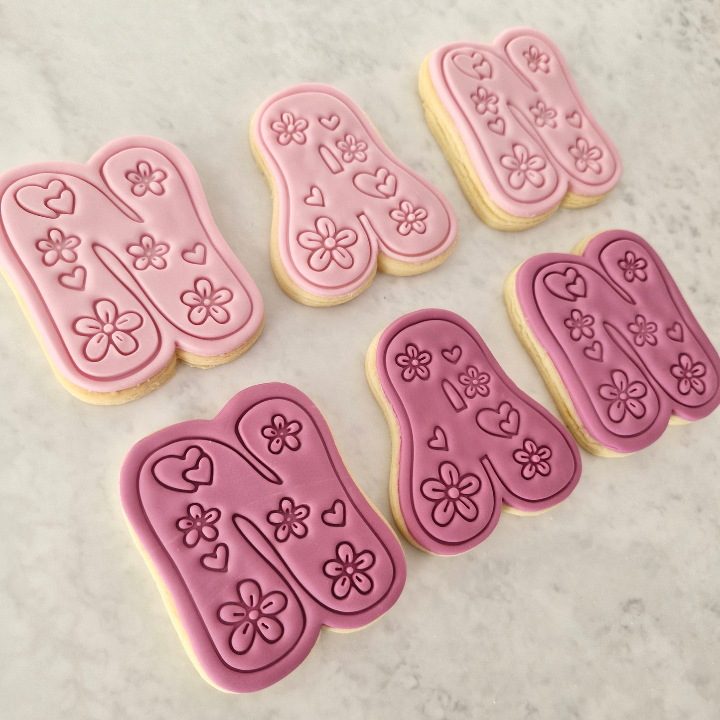 Groovy Nan Cookie Cutter and Stamp Set cookies on the side spelling nan in two colours light pink and dark pink on white marble backgound