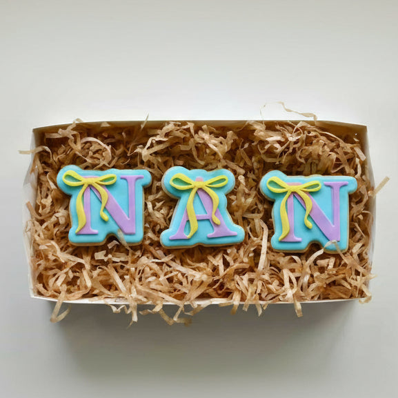 Box of cookies shaped like the letters 'NAN' with colorful icing on a white background  Nan with Bow Cookie Cutter and Stamp