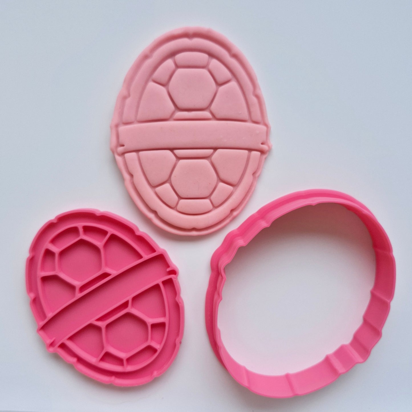 pink fondant, pink cookie cutter and stamp of a turtle shell, on white background