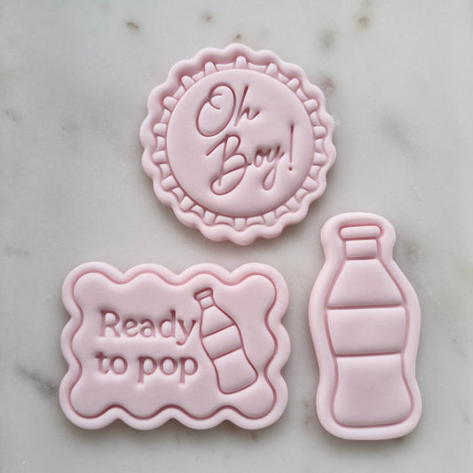 Oh Boy Ready to Pop Set Cookie Cutter and Stamp designs in pink fondant on marble surface.