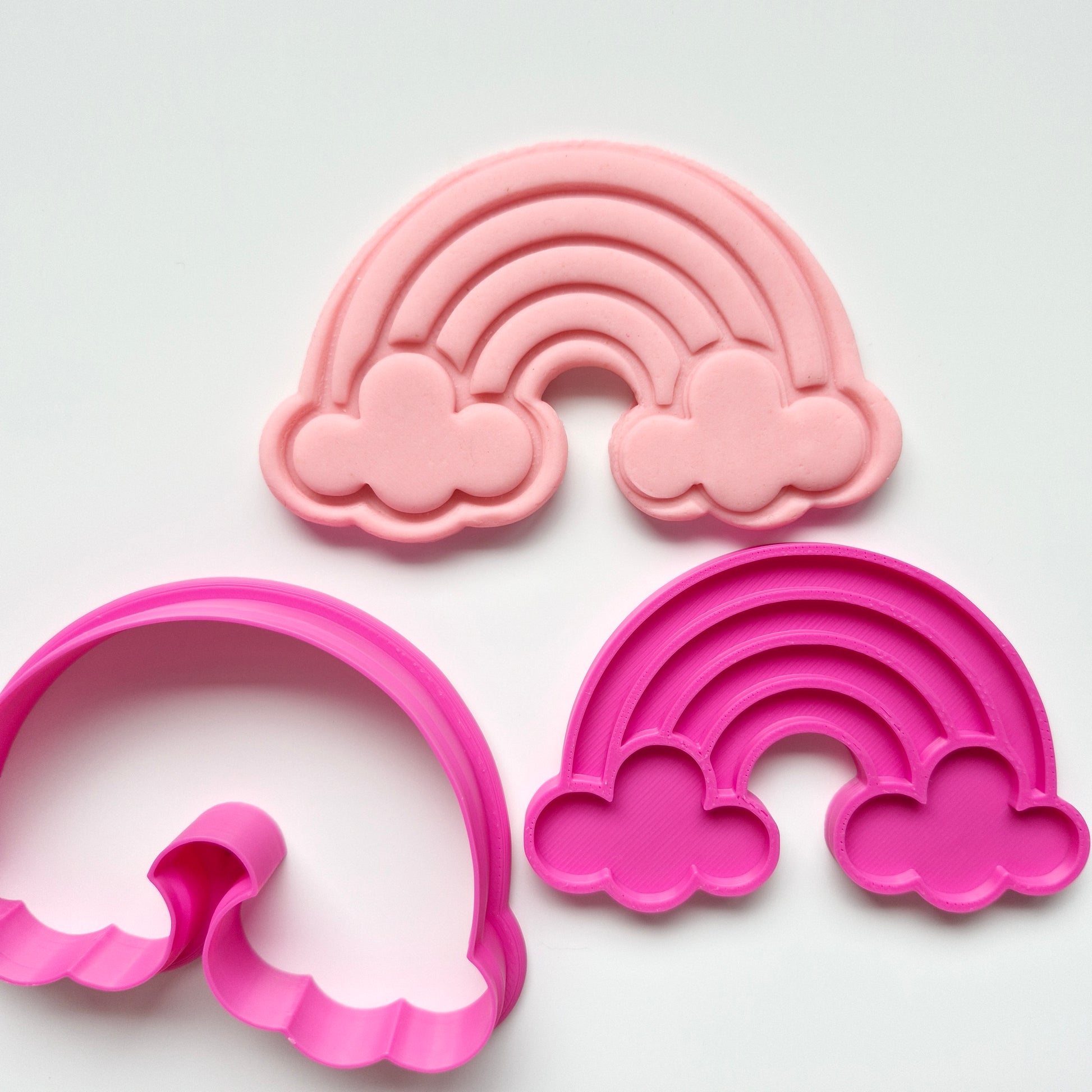rainbow with two clouds in the format of one a light pink fondant stamp and hot pink of cookie cutter and stamp on white background