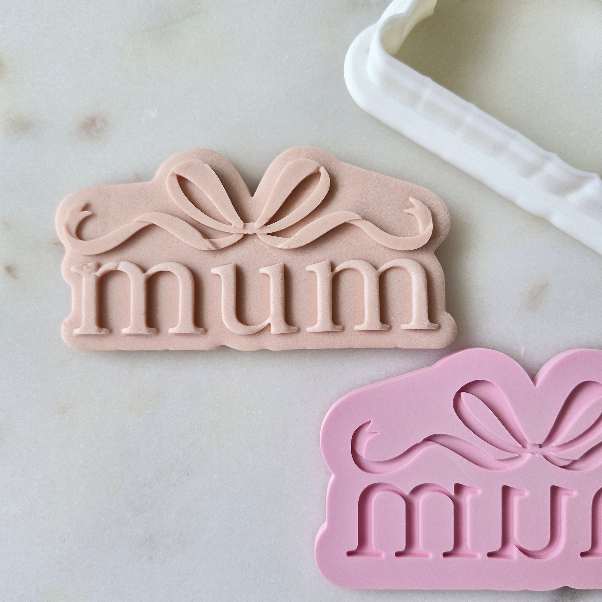 Mum With Bow Cookie Cutter and Stamp zoomed out and on white marble background