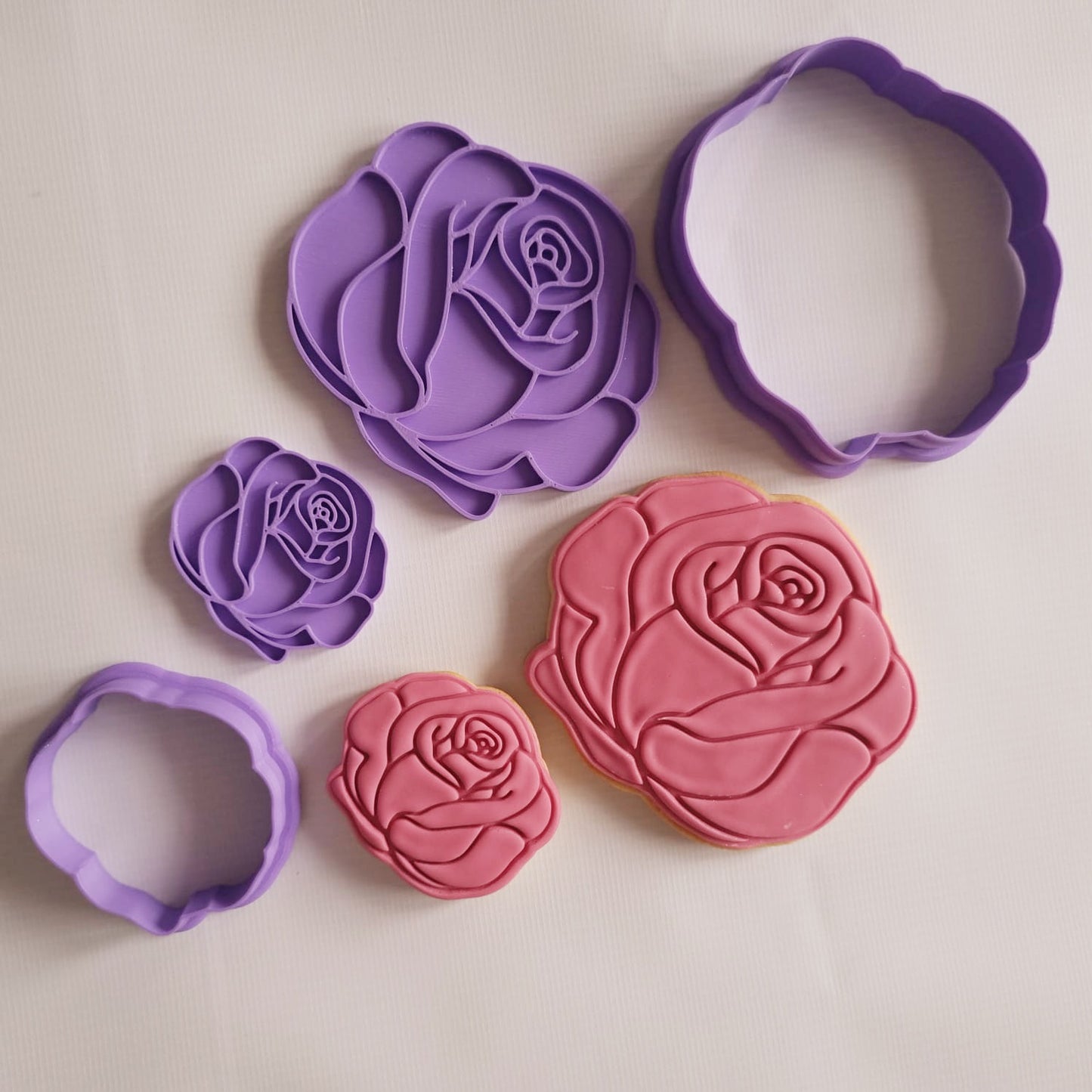 rose flower cookie cutter and stamp in small and big alongside small and big sugar cookies in red