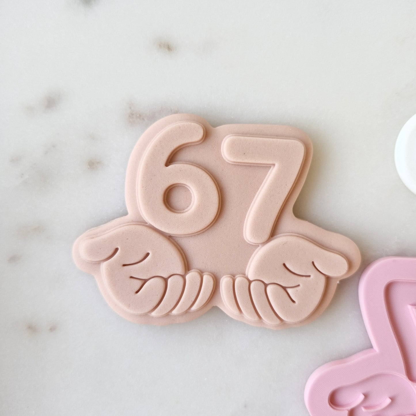 Six Seven 6 7 Cookie Cutter and Deboss Stamp numbers help in hands on white marble background zoomed in 