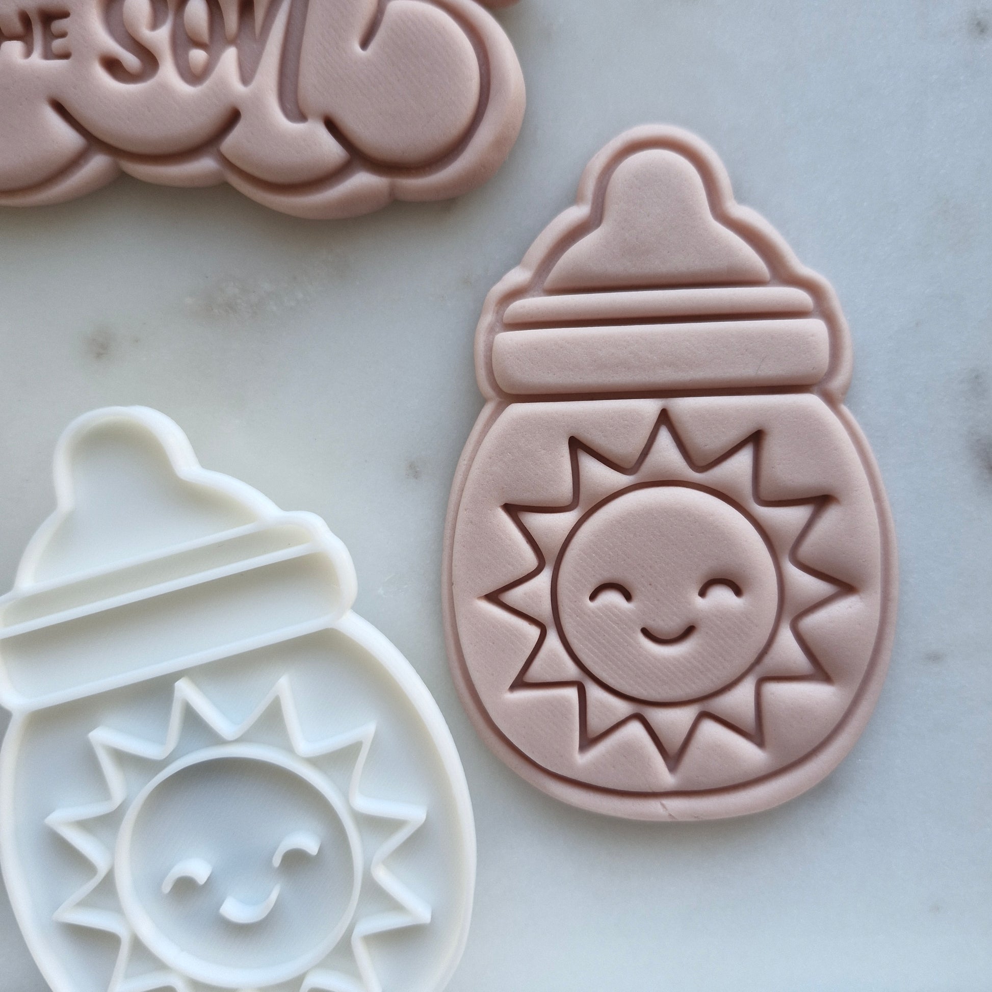 Smiling Sun Cookie Cutter and Emboss Stamp - Baking Tool, zoomed out, marble background Here Comes the Son Set Cookie Cutter and Emboss Stamp - Baking Tool Here Comes the Son Set Cookie Cutter and Stamp Baking Tool  Baby Bottle with Sun Cookie Cutter and Emboss Stamp - Baking Tool