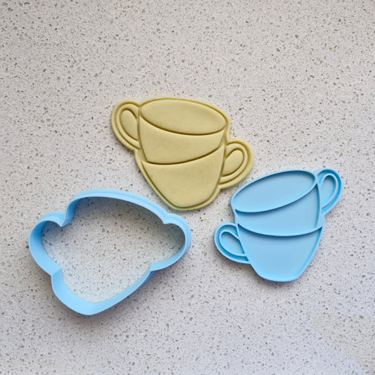 stacked teacups, in the format of yellow fondant, blue cookie cutter and stamp, on white speckled stone