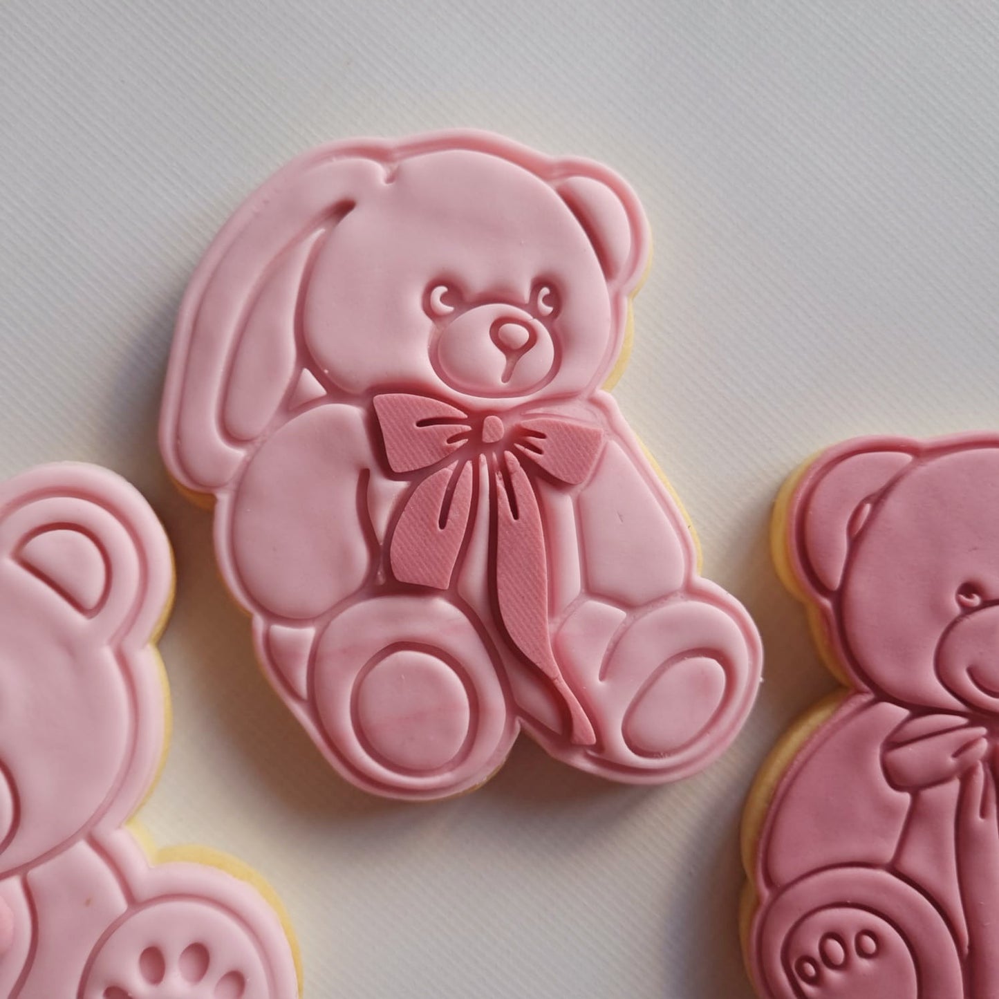 sugar cookie in the shape of teddy bear with fondant on and white Bear with long Bow Cookie Cutter and Stampbackground